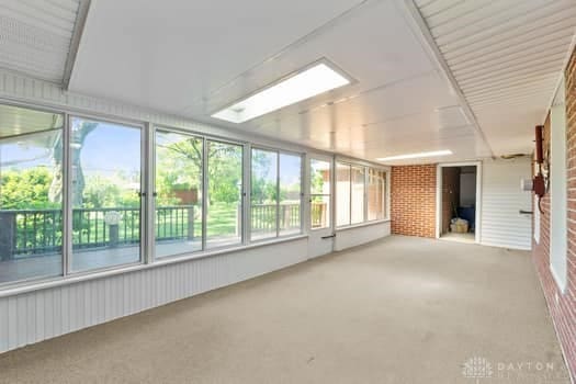 1108 Donson Dr, Kettering, OH 45429 - unfurnished sunroom with brick wall, plenty of natural light, and carpet floors