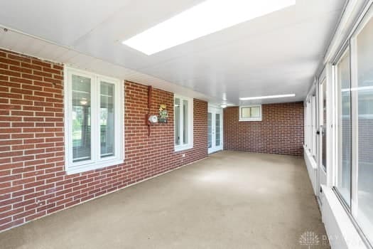 1108 Donson Dr, Kettering, OH 45429 - unfurnished sunroom featuring brick wall, carpet, and plenty of natural light