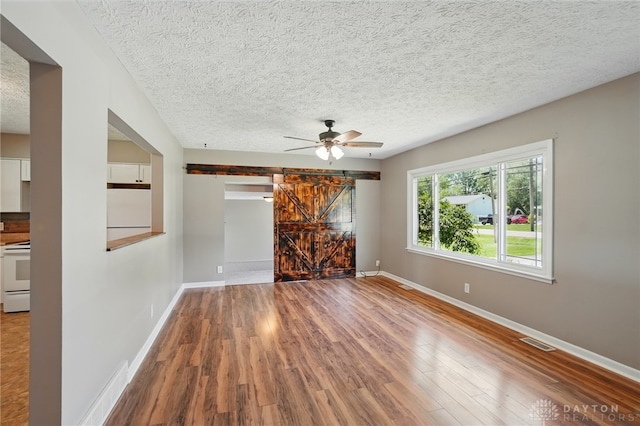 6726 Middletown Germantown Rd, Middletown, OH 45042 - unfurnished room featuring a barn door, baseboards, wood finished floors, a textured ceiling, and a ceiling fan