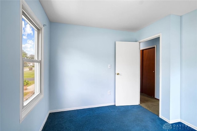 1385 Kylemore Dr, Xenia, OH 45385 - unfurnished bedroom with multiple windows, dark colored carpet, and baseboards