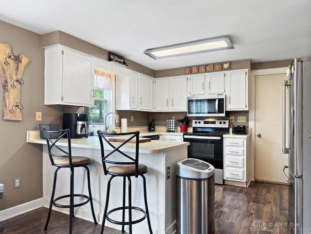 1277 Yocom Rd, Cable, OH 43009 - kitchen featuring stainless steel appliances, a peninsula, white cabinets, light countertops, and dark wood-type flooring