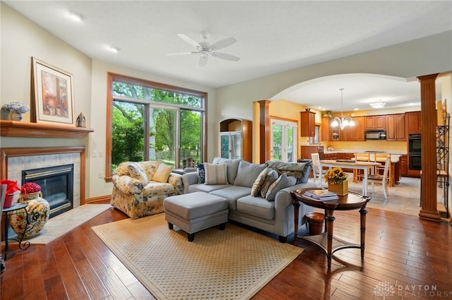 1403 Timshel St, Sugarcreek Township, OH 45440 - living room with ornate columns, arched walkways, a tiled fireplace, a ceiling fan, and hardwood / wood-style flooring
