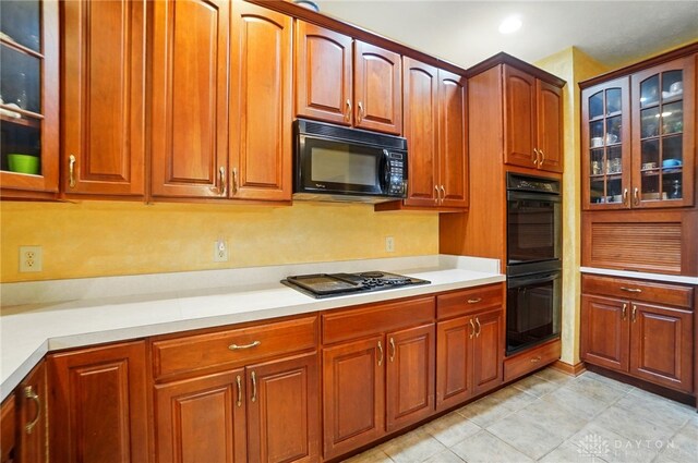 1403 Timshel St, Sugarcreek Township, OH 45440 - kitchen featuring black appliances, light countertops, glass insert cabinets, and brown cabinets