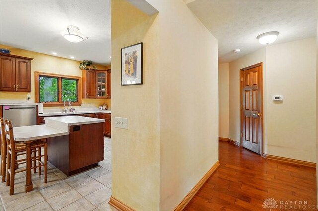 1403 Timshel St, Sugarcreek Township, OH 45440 - kitchen featuring dishwasher, a kitchen bar, light countertops, a sink, and baseboards