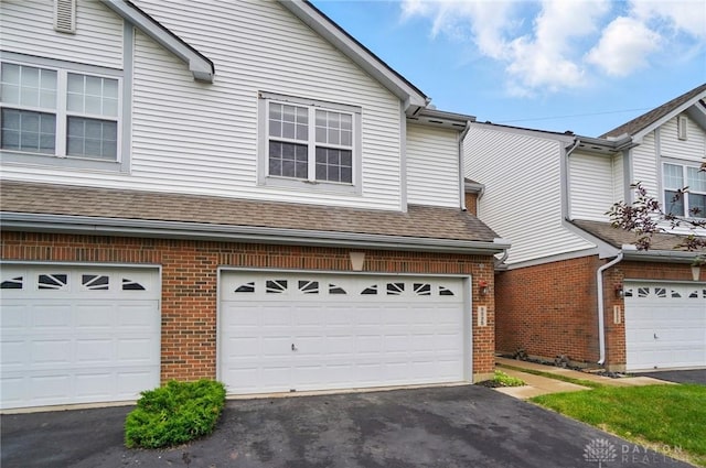 9235 Great Lakes Cir, Washington Twp, OH 45458 - view of front of house with brick siding, a garage, driveway, and roof with shingles