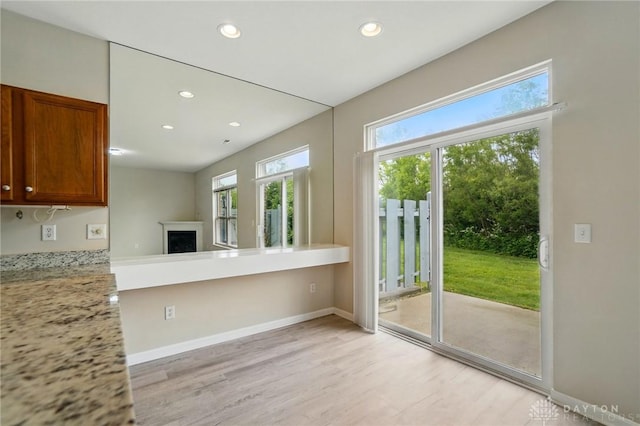 9235 Great Lakes Cir, Washington Twp, OH 45458 - kitchen with light wood-style flooring, recessed lighting, brown cabinets, a fireplace, and baseboards