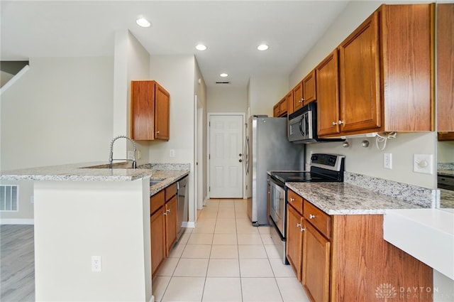 9235 Great Lakes Cir, Washington Twp, OH 45458 - kitchen with stainless steel appliances, brown cabinetry, a peninsula, light stone countertops, and recessed lighting