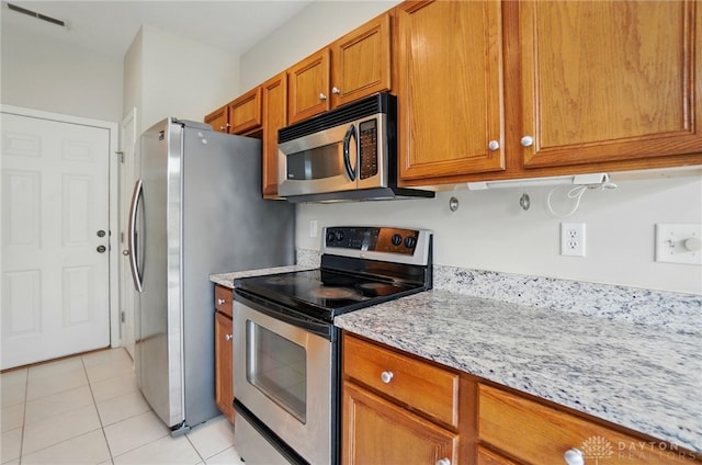 9235 Great Lakes Cir, Washington Twp, OH 45458 - kitchen featuring appliances with stainless steel finishes, brown cabinets, light tile patterned flooring, and light stone countertops
