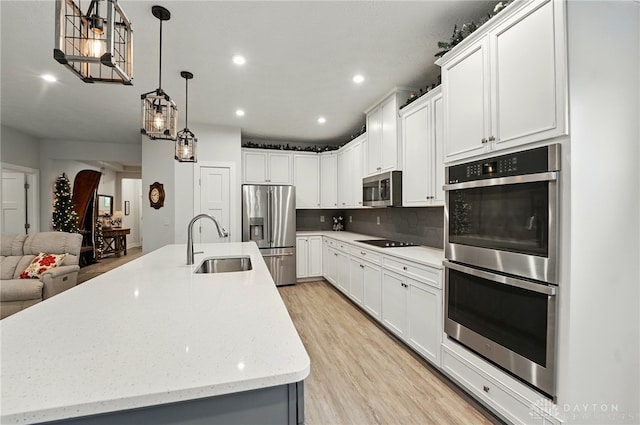9777 Winding Creek Blvd, Clearcreek Twp, OH 45458 - kitchen with appliances with stainless steel finishes, a sink, tasteful backsplash, a kitchen island with sink, and light wood-type flooring