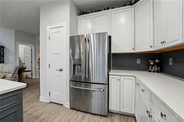 9777 Winding Creek Blvd, Clearcreek Twp, OH 45458 - kitchen with stainless steel refrigerator with ice dispenser, decorative backsplash, light wood-style flooring, and white cabinets
