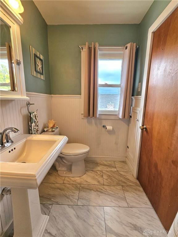 1800 Patterson Rd, Dayton, OH 45420 - half bath with marble look tile flooring, plenty of natural light, toilet, and wainscoting