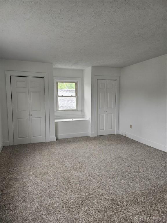 1800 Patterson Rd, Dayton, OH 45420 - unfurnished bedroom with a textured ceiling, carpet flooring, baseboards, and two closets