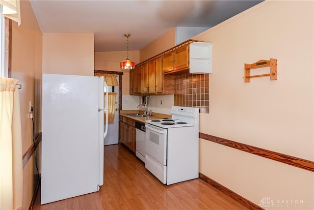 903 Kennison Ave, New Carlisle, OH 45344 - kitchen featuring white appliances, light wood finished floors, brown cabinets, a sink, and hanging light fixtures