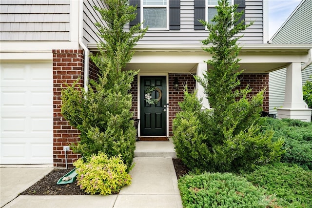 148 Oasis Ct, Springboro, OH 45066 - view of exterior entry featuring brick siding, a garage, and covered porch