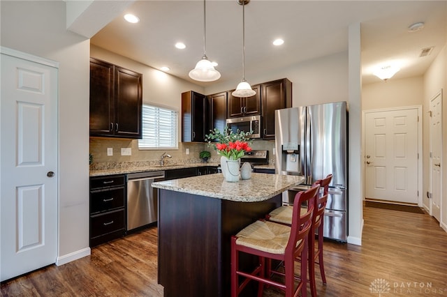 148 Oasis Ct, Springboro, OH 45066 - kitchen with stainless steel appliances, a kitchen breakfast bar, dark brown cabinetry, decorative backsplash, and pendant lighting