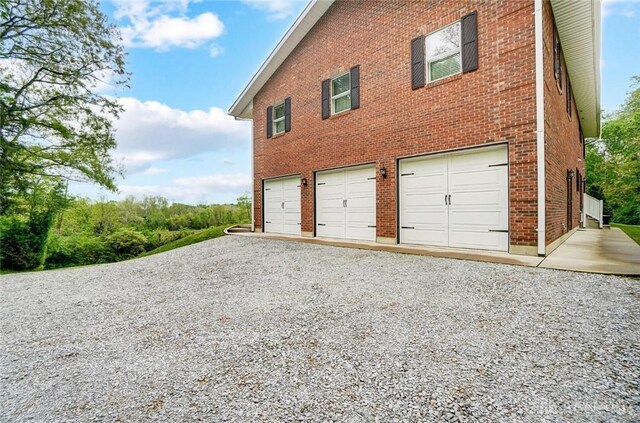 5829 Watt Rd, Camden, OH 45311 - view of property exterior featuring a garage, driveway, and brick siding