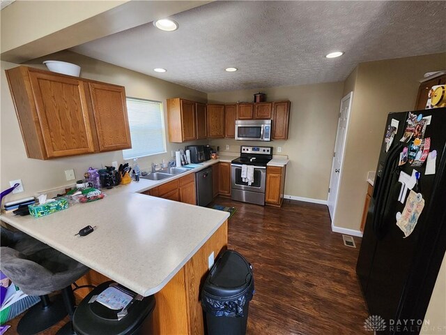 2380 Patterson Ln, Troy, OH 45373 - kitchen with stainless steel appliances, a peninsula, brown cabinetry, light countertops, and recessed lighting