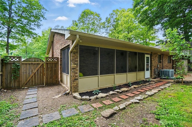 2942 Stauffer Dr, Beavercreek, OH 45434 - view of home's exterior featuring a gate, brick siding, central AC unit, and a sunroom