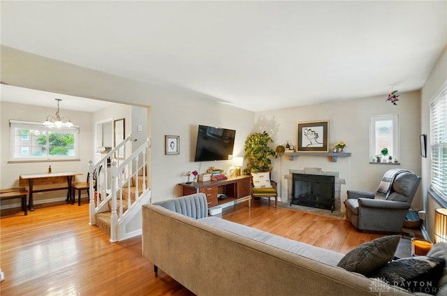 448 Triangle Ave, Oakwood, OH 45419 - living room with a fireplace with flush hearth, light wood finished floors, a chandelier, and stairs