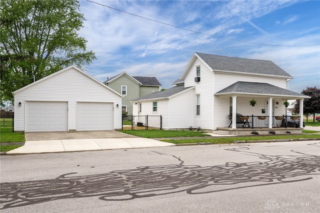 602 W N St, Arcanum, OH 45304 - view of front of home with covered porch, an outbuilding, a shingled roof, and a detached garage