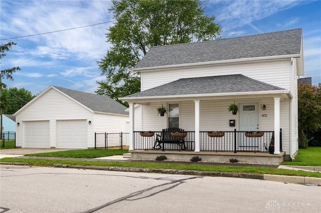602 W N St, Arcanum, OH 45304 - view of front of house featuring covered porch, a detached garage, an outdoor structure, and a shingled roof