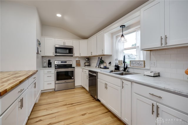602 W N St, Arcanum, OH 45304 - kitchen featuring appliances with stainless steel finishes, a sink, lofted ceiling, tasteful backsplash, and white cabinetry