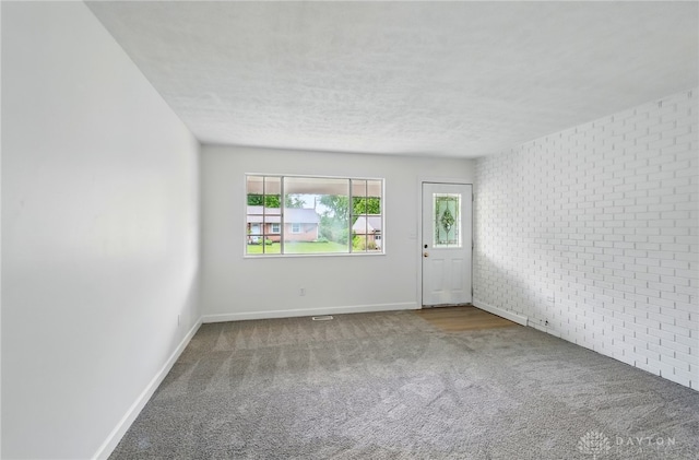 2424 Pinegrove Dr, Dayton, OH 45449 - empty room with carpet, baseboards, a textured ceiling, and brick wall
