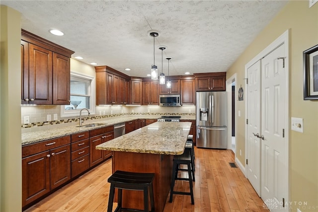 10550 Willow Brook Rd, Dayton, OH 45458 - kitchen with stainless steel appliances, a sink, a kitchen breakfast bar, decorative backsplash, and light stone countertops