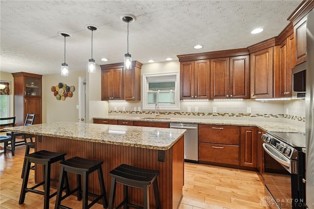 10550 Willow Brook Rd, Dayton, OH 45458 - kitchen featuring appliances with stainless steel finishes, a sink, light wood-type flooring, a textured ceiling, and decorative backsplash