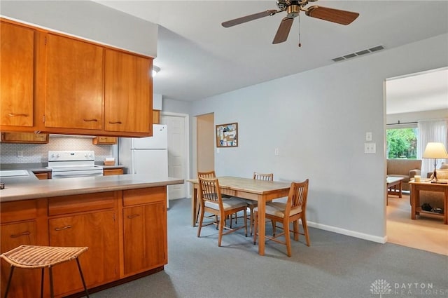 600 Deauville Dr, Washington Twp, OH 45429 - kitchen with white appliances, carpet floors, ceiling fan, backsplash, and brown cabinets