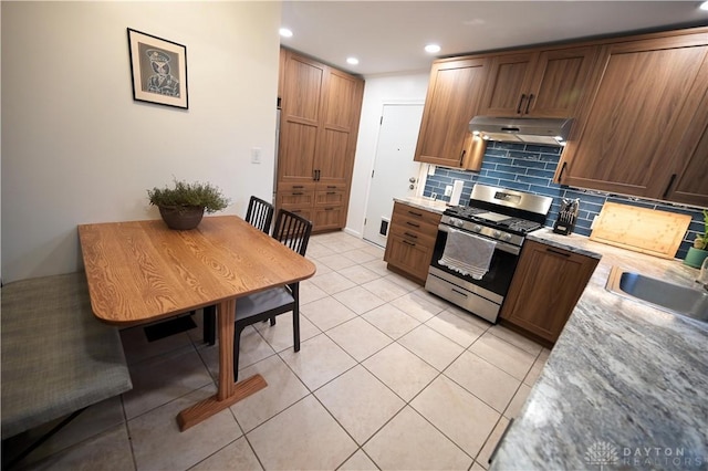 1265 Jeanette Dr, Dayton, OH 45432 - kitchen featuring stainless steel gas range oven, under cabinet range hood, backsplash, recessed lighting, and light tile patterned floors