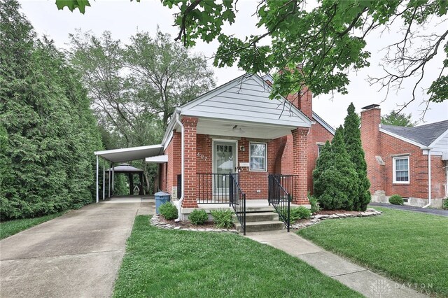 407 Claranna Ave, Oakwood, OH 45419 - bungalow-style house with brick siding, concrete driveway, a front yard, a chimney, and a carport