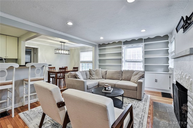 407 Claranna Ave, Oakwood, OH 45419 - living area with a fireplace, a textured ceiling, light wood-style flooring, crown molding, and recessed lighting