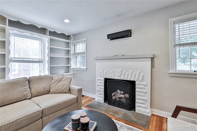 407 Claranna Ave, Oakwood, OH 45419 - living room with wood finished floors, plenty of natural light, a textured ceiling, a fireplace with flush hearth, and built in shelves