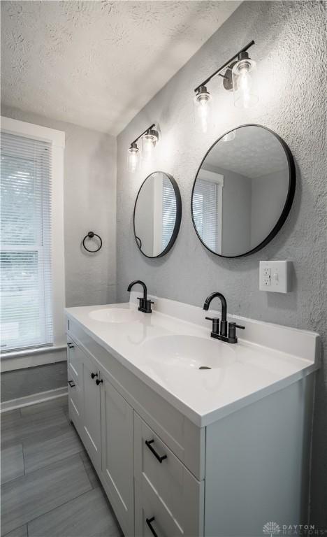 522 Pennsylvania Ave, Troy, OH 45373 - bathroom with double vanity, a textured ceiling, a textured wall, and baseboards
