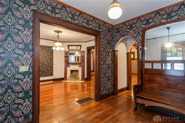 1628 E 5th St, Dayton, OH 45403 - hall with arched walkways, wood finished floors, wallpapered walls, baseboards, and crown molding