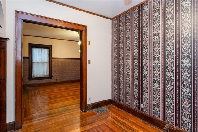 1628 E 5th St, Dayton, OH 45403 - empty room featuring wood finished floors, crown molding, baseboards, wainscoting, and wallpapered walls