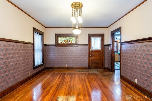 1628 E 5th St, Dayton, OH 45403 - unfurnished dining area featuring wood-type flooring, wainscoting, baseboards, ornamental molding, and wallpapered walls