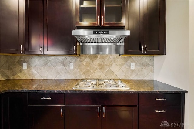 9752 Crooked Creek Dr, Centerville, OH 45458 - kitchen with exhaust hood, stainless steel gas stovetop, tasteful backsplash, dark stone counters, and glass insert cabinets