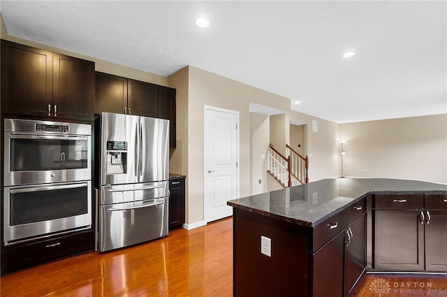 9752 Crooked Creek Dr, Centerville, OH 45458 - kitchen featuring appliances with stainless steel finishes, wood finished floors, dark brown cabinets, recessed lighting, and dark stone counters