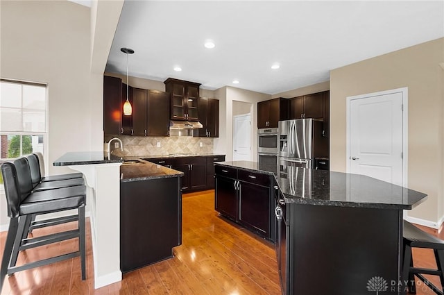 9752 Crooked Creek Dr, Centerville, OH 45458 - kitchen with appliances with stainless steel finishes, a sink, a kitchen bar, light wood-style flooring, and recessed lighting