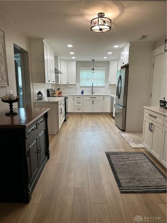 2419 Meadow Green Dr, Beavercreek, OH 45431 - kitchen featuring appliances with stainless steel finishes, light wood-style flooring, white cabinets, backsplash, and pendant lighting