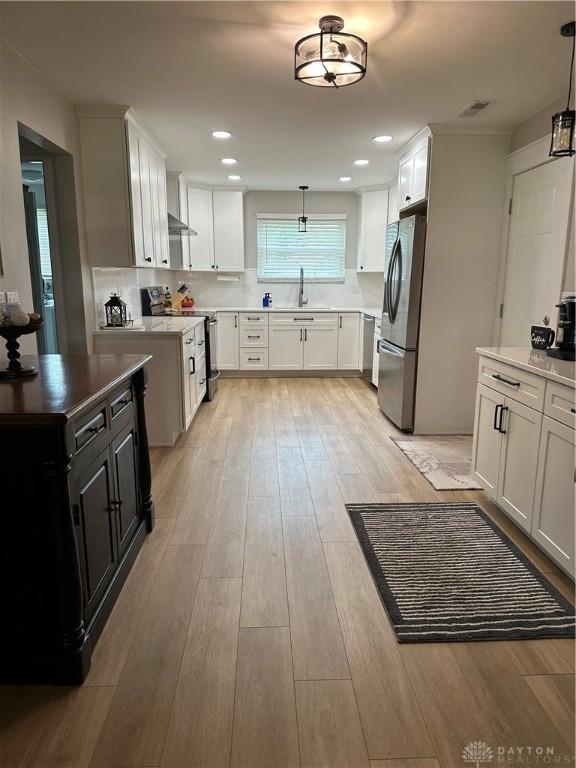 2419 Meadow Green Dr, Beavercreek, OH 45431 - kitchen with stainless steel appliances, light wood-type flooring, a sink, decorative light fixtures, and recessed lighting