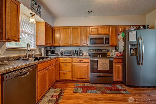 286 Chamberlin Dr, Hamilton, OH 45013 - kitchen with appliances with stainless steel finishes, a sink, brown cabinetry, dark wood-style flooring, and dark countertops