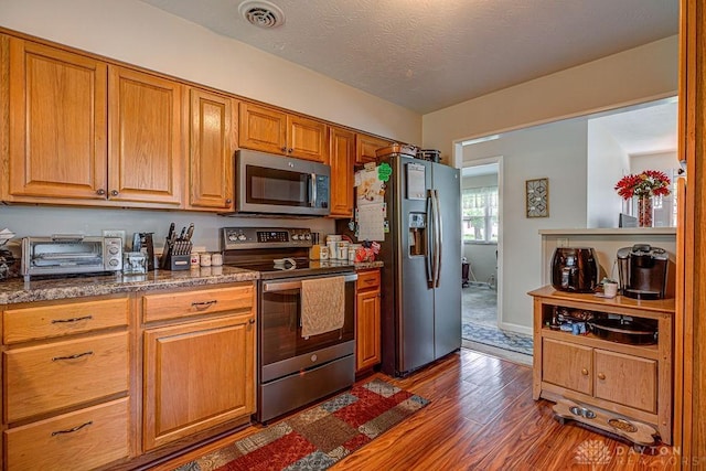 286 Chamberlin Dr, Hamilton, OH 45013 - kitchen with stainless steel appliances, dark wood-style floors, brown cabinetry, and dark stone counters