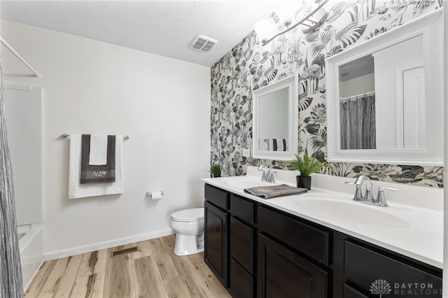 109 Waterford Blvd, Fairborn, OH 45324 - bathroom featuring wallpapered walls, double vanity, wood finished floors, and a textured ceiling