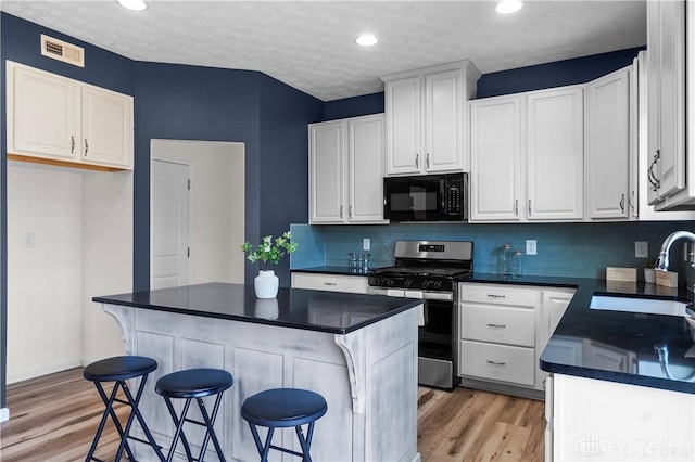 109 Waterford Blvd, Fairborn, OH 45324 - kitchen featuring black microwave, stainless steel gas range oven, dark countertops, light wood-style flooring, and recessed lighting