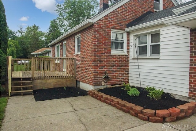 3145 Mohican Ave, Kettering, OH 45429 - view of home's exterior with a deck, brick siding, and a chimney