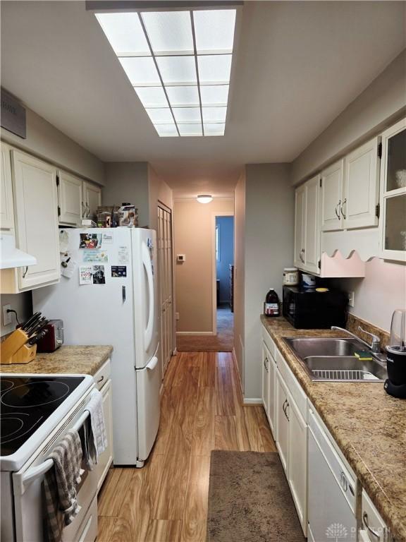 1008 Terracewood Dr, Englewood, OH 45322 - kitchen with a sink, under cabinet range hood, white appliances, light wood-style flooring, and white cabinetry