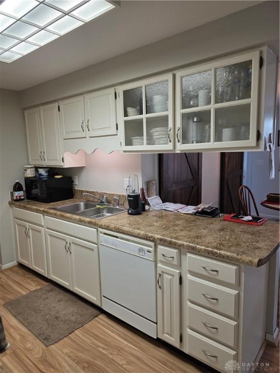 1008 Terracewood Dr, Englewood, OH 45322 - kitchen featuring dishwasher, black microwave, light wood-type flooring, a sink, and white cabinets